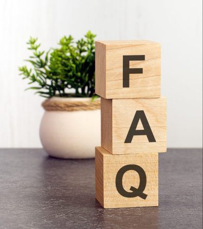 letters of the alphabet of FAQ on wooden cubes, green plant on a white background. FAQ - short for Frequency Asked Questions